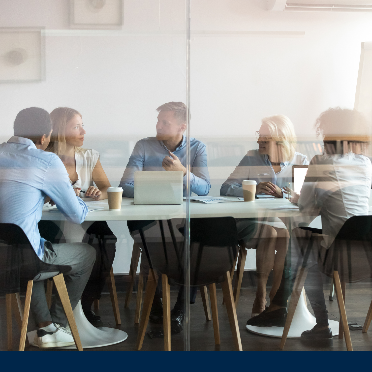 A photograph of people conversing in a conference room.