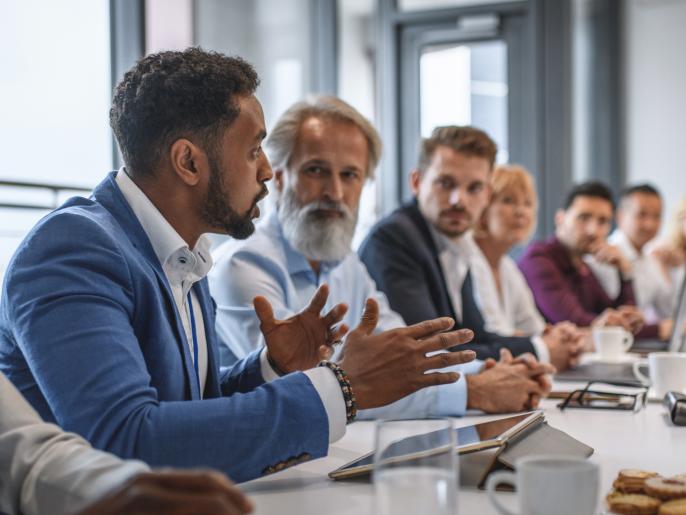 Business person expressing opinions to junior and senior colleagues in conference room