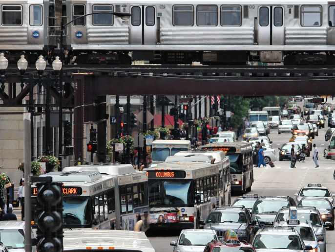 Photograph of a busy city showing cars, busses, and rail cars.