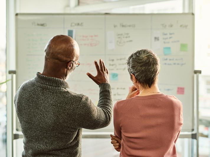 Businesspeople standing together and using a white board during a discussion in the office