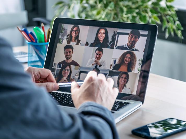 Employee speaking on video call with colleagues on online briefing with laptop at home