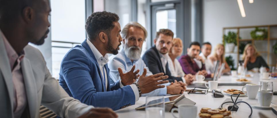 Business person expressing opinions to junior and senior colleagues in conference room